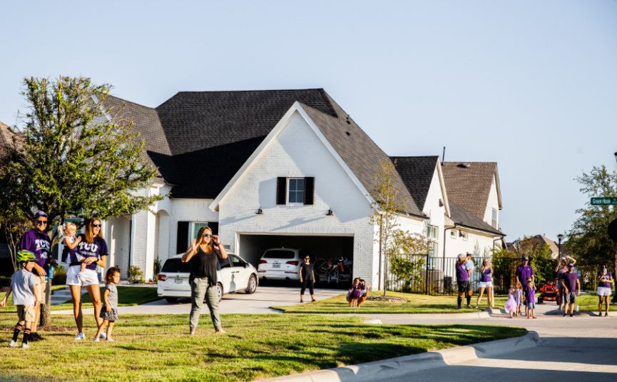 Neighbors gather outside and cheer during the drive-by