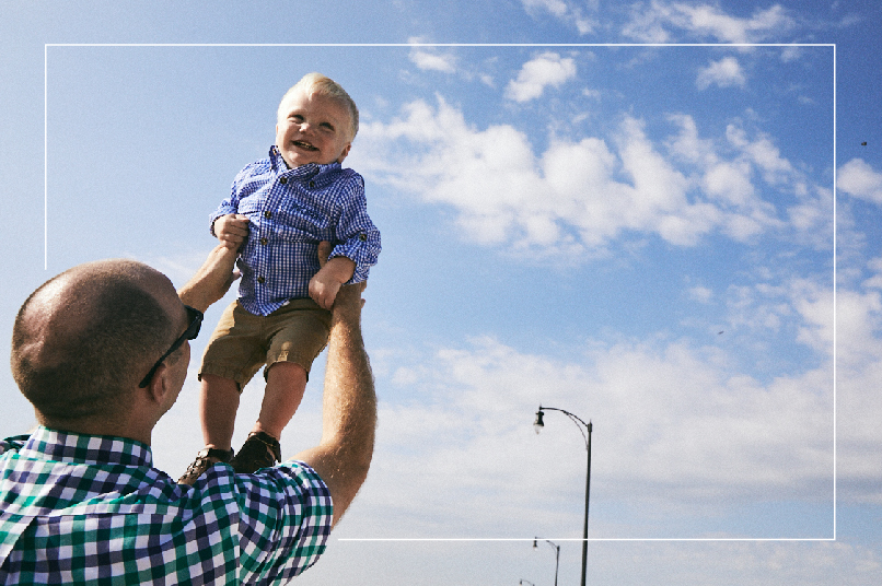 Dad lifts his youngest son into the air, who is grinning from ear to ear.